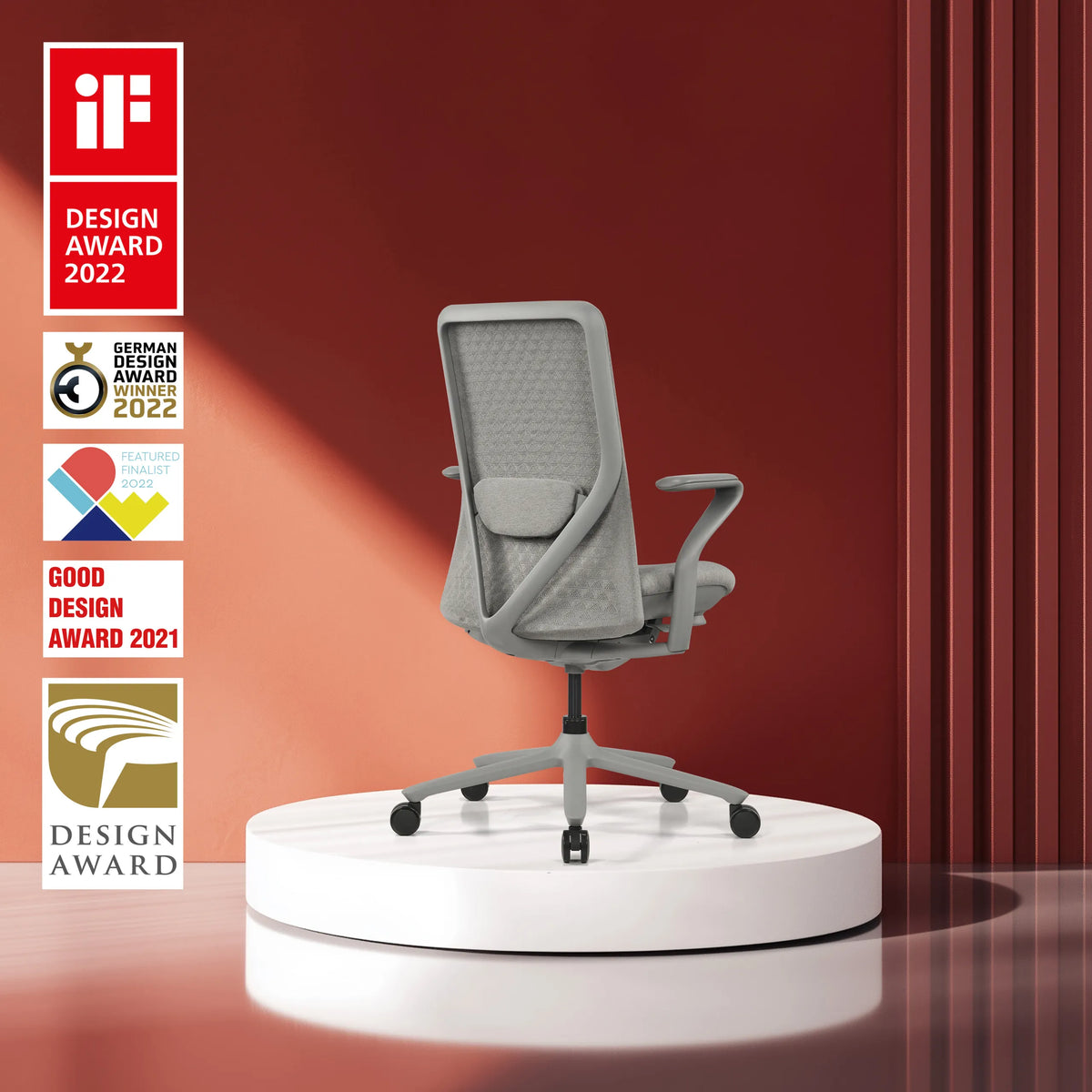 Grå High End kontorstol VERVIO med netryglæn på en hvid sokkel foran en rød baggrund fra hjh OFFICE