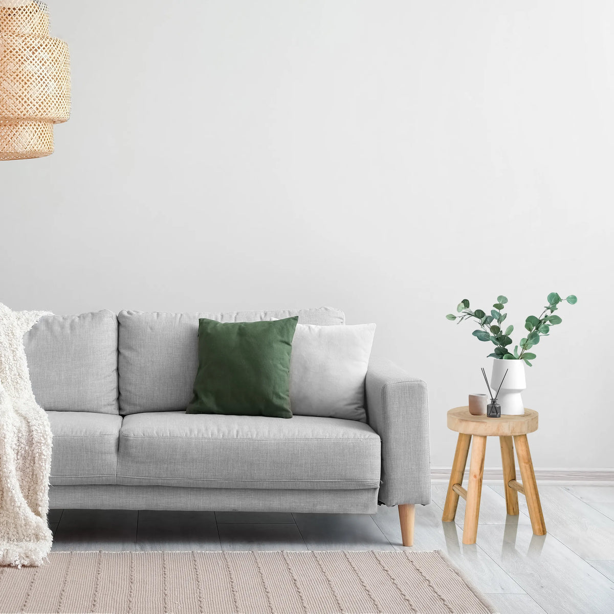Brun træskammel RUSTIKO W som sidebord ved siden af en grå sofa fra hjh LIVING