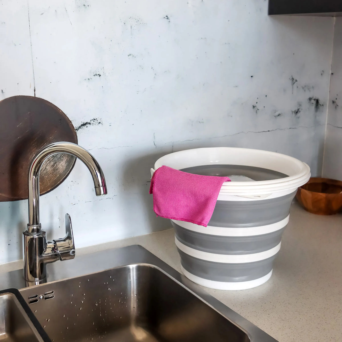 Gråhvid Foldbar beholder CLEAN SILR med en lyserød klud på en arbejdsflade ved siden af en vask fra hjh OFFICE