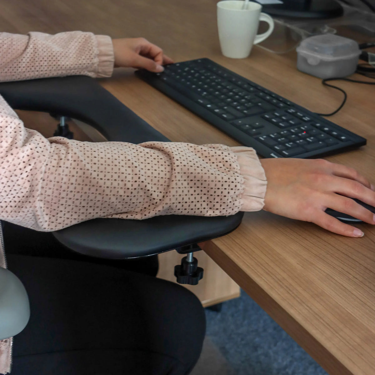 Sort armlæn fra model RELEX RT2 på et skrivebord med tastatur og mus fra hjh OFFICE