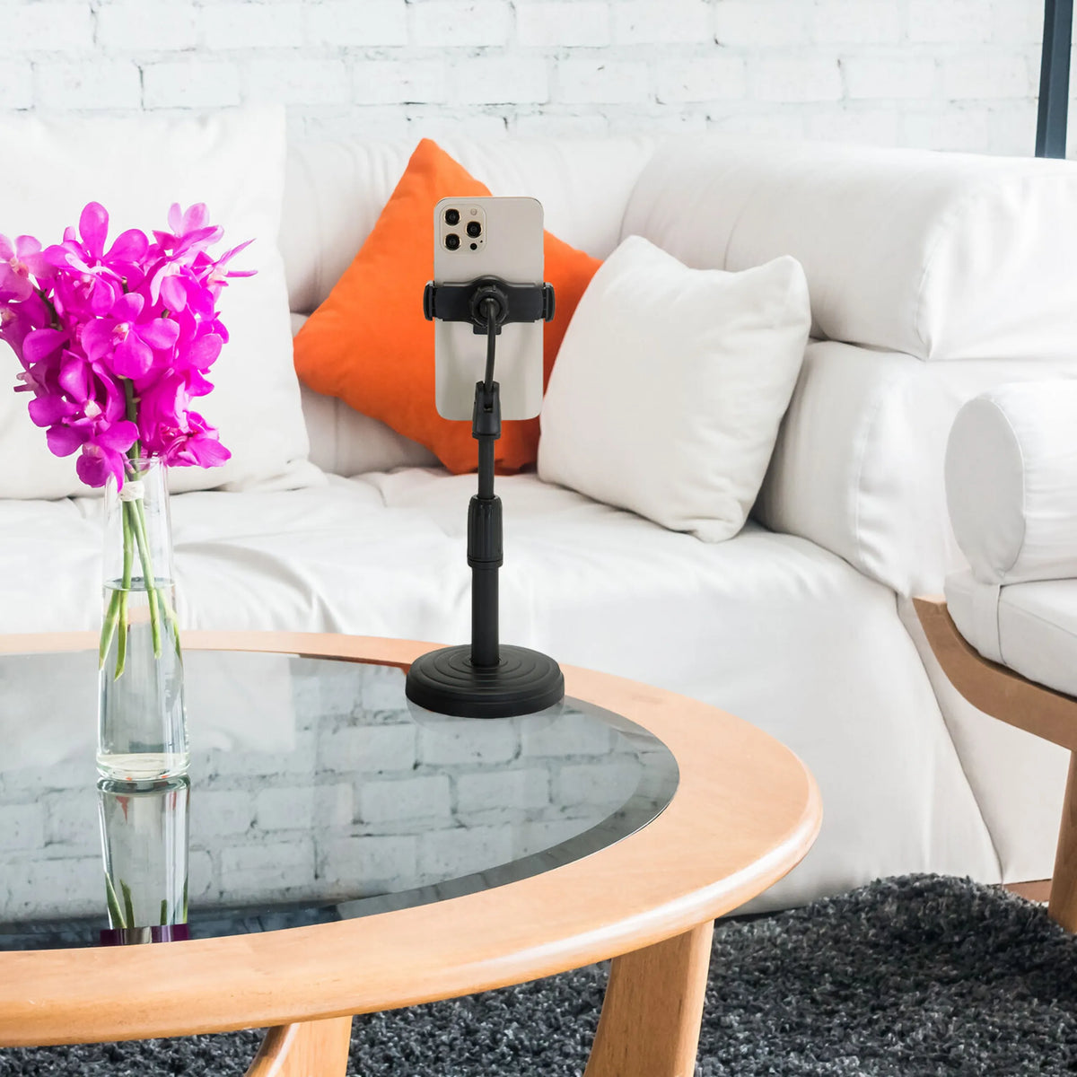 Sort holder til mobiltelefon & tablet FLEXMOBI II med smartphone på et glasbord foran en hvid sofa fra hjh OFFICE