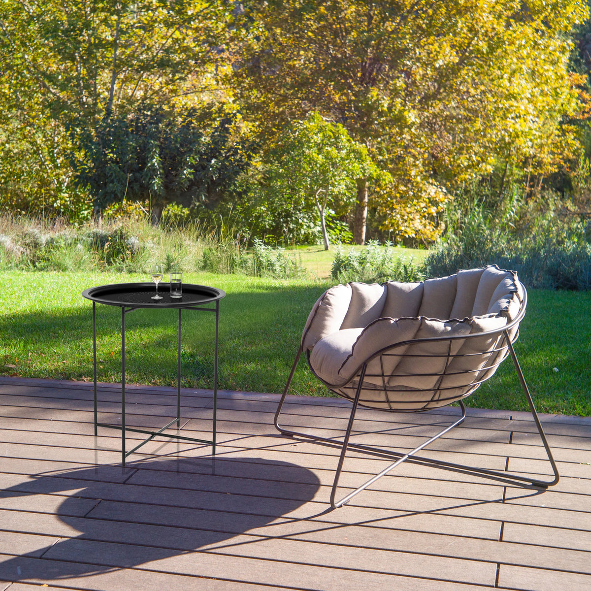 Sort sidebord ALLRUND i metal med hulmønster på en terrasse ved siden af en loungestol fra hjh LIVING