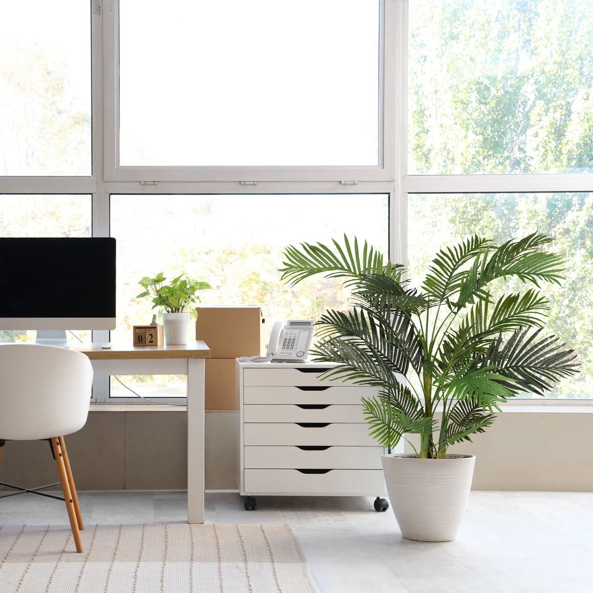 Grøn kunstig plante ARECA II i en hvid potte ved siden af en hvid rullecontainer fra hjh OFFICE