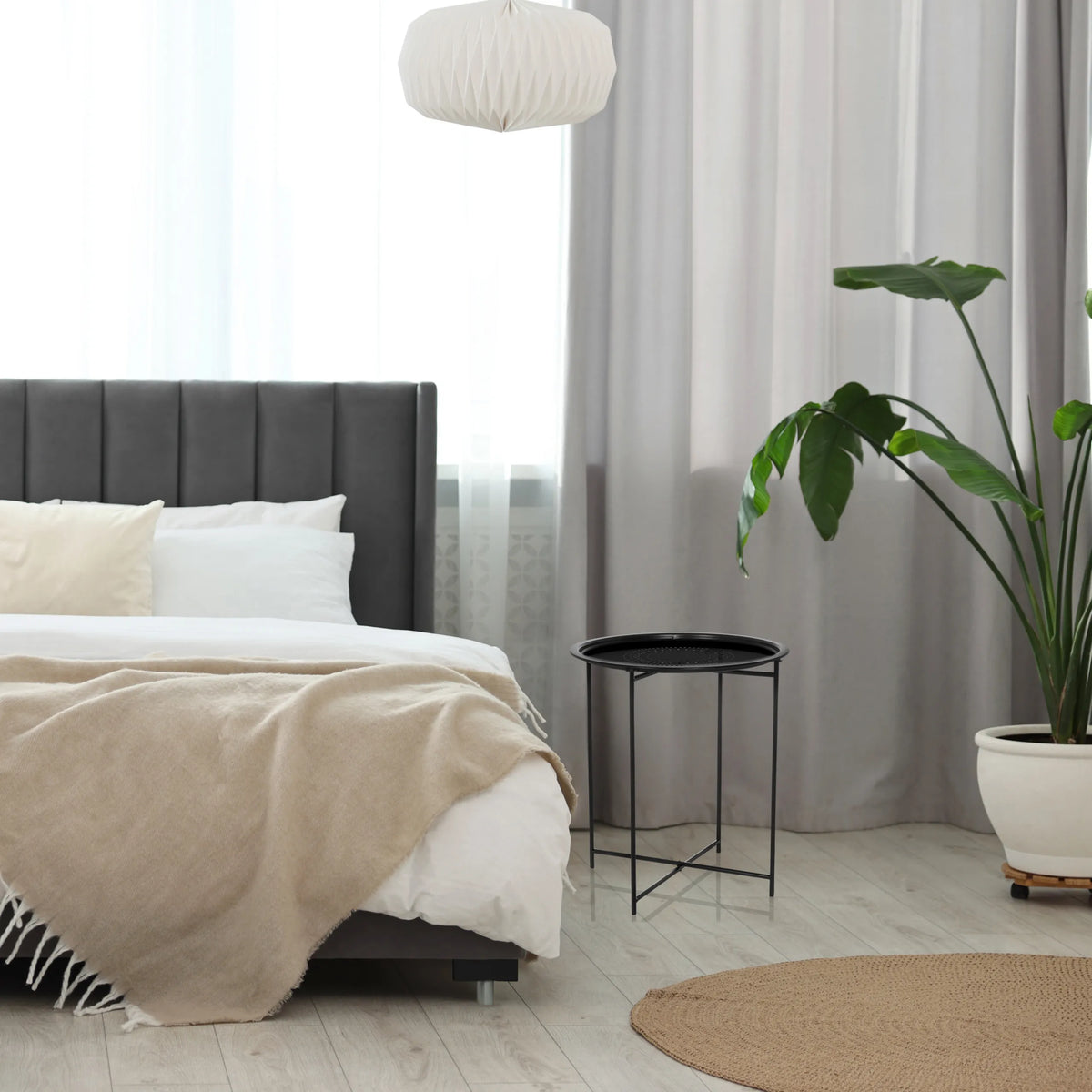 Sort ALLRUND sidebord i metal med en perforeret plade ved siden af en seng fra hjh LIVING