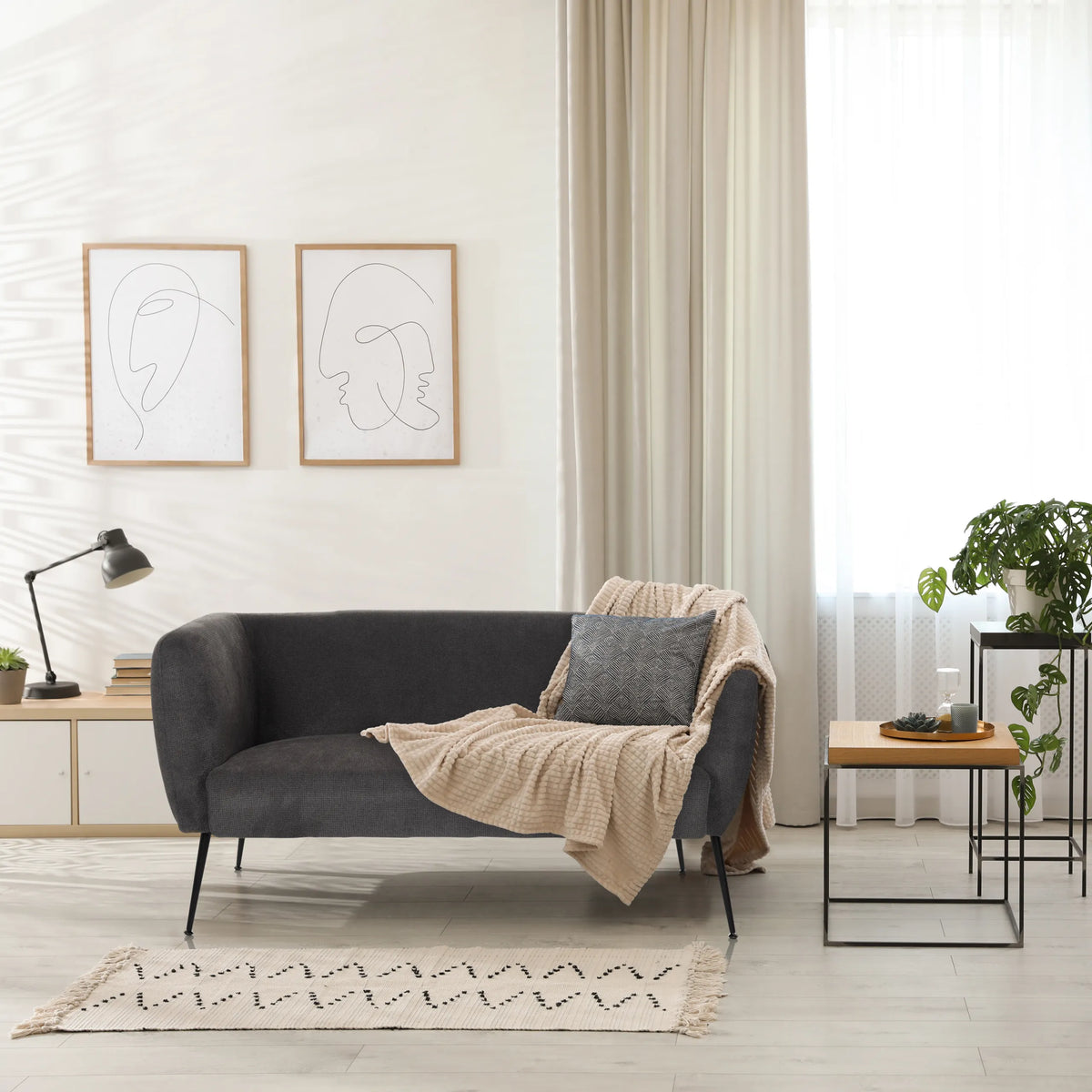 Graues Loungesofa HAYRIVER mit Kissen und Decke in einem hellen Raum von hjh LIVING