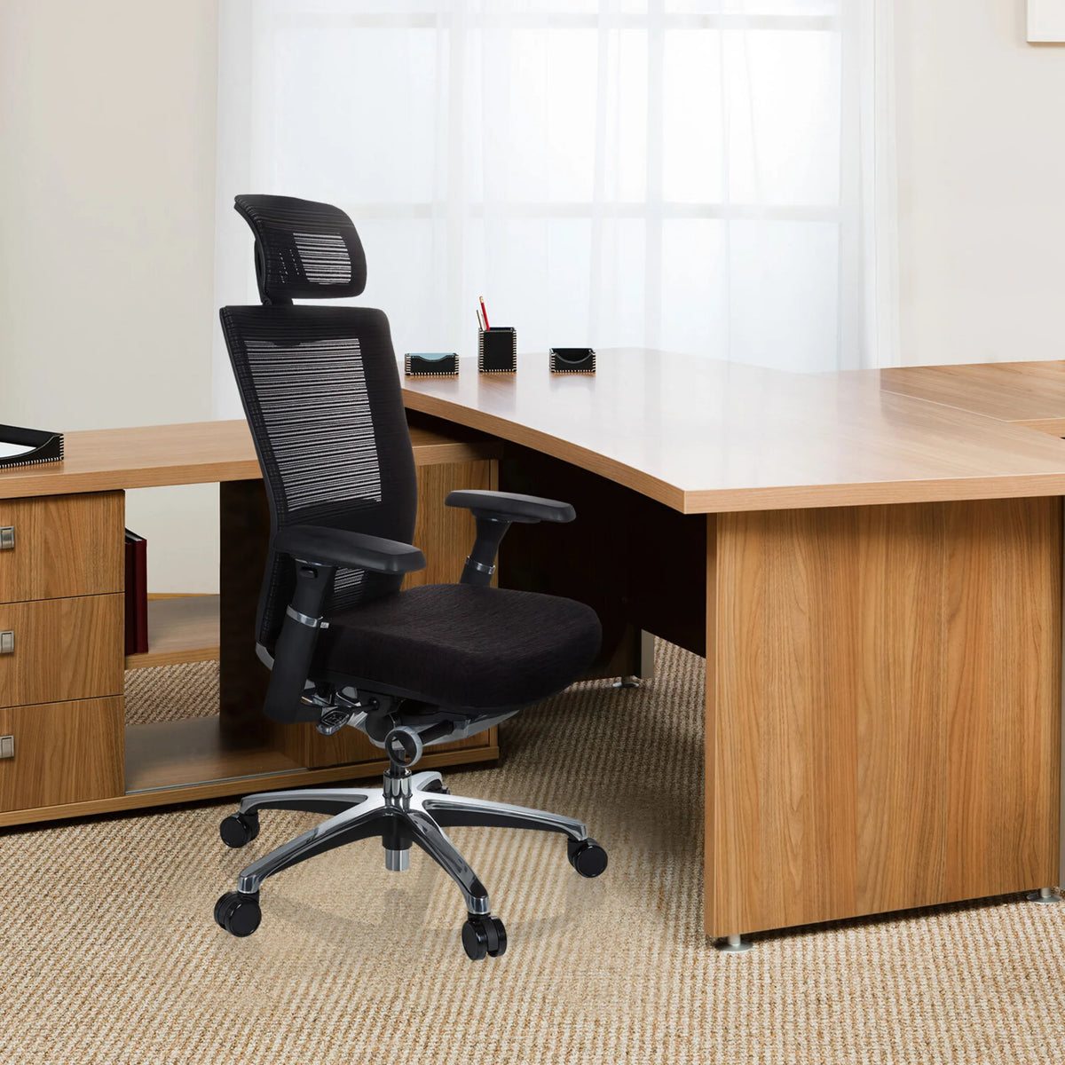 Sort High End kontorstol NOVA PRO I med mesh-ryglæn og nakkestøtte foran et skrivebord fra hjh OFFICE