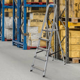 Femtrins foldestige SOLID III i aluminium i et lager foran en reol fra hjh OFFICE