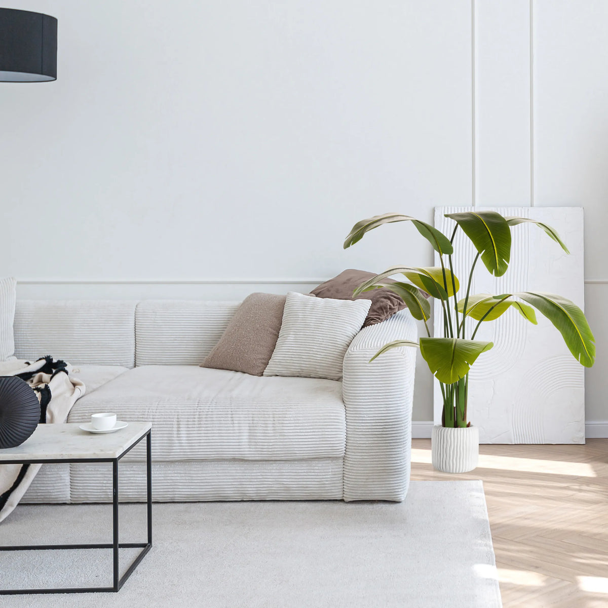 Grøn Kunstige plante BANANE i en hvid potte ved siden af en sofa fra hjh OFFICE