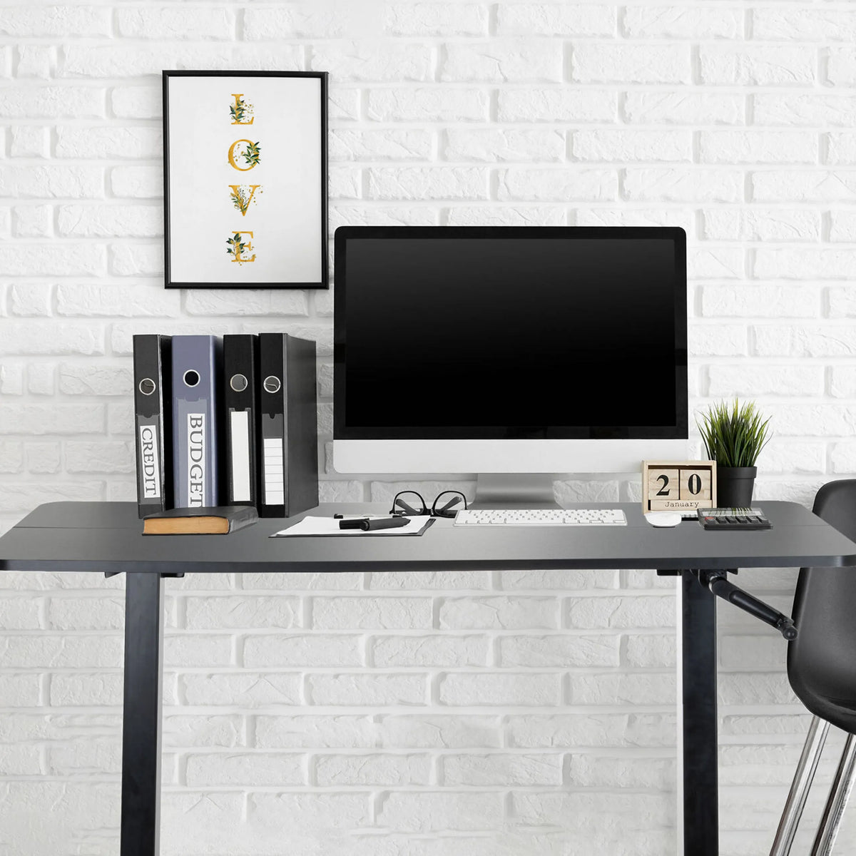 Sort ståskrivebord STAND CR med skærm, tastatur og ringbind foran en hvid murstensvæg fra hjh OFFICE