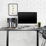 Sort ståskrivebord STAND CR med skærm, tastatur og ringbind foran en hvid murstensvæg fra hjh OFFICE
