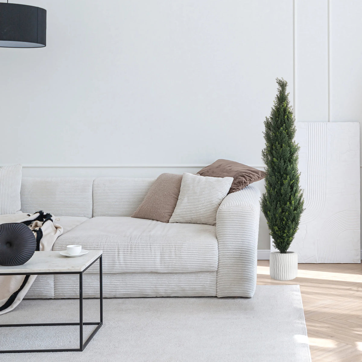 Grøn kunstig plante CEDRUS i en hvid potte ved siden af en hvid sofa fra hjh OFFICE