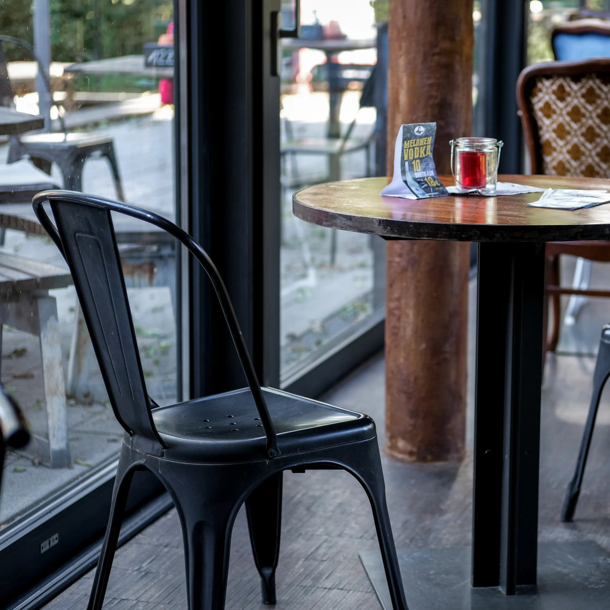 Sort Bistrostol VANTAGGIO BRUSH med buet ryglæn ved et rundt bord fra hjh OFFICE