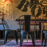 Bagsiden af en sort VANTAGGIO BRUSH bistrostol i metal ved et bord fra hjh OFFICE