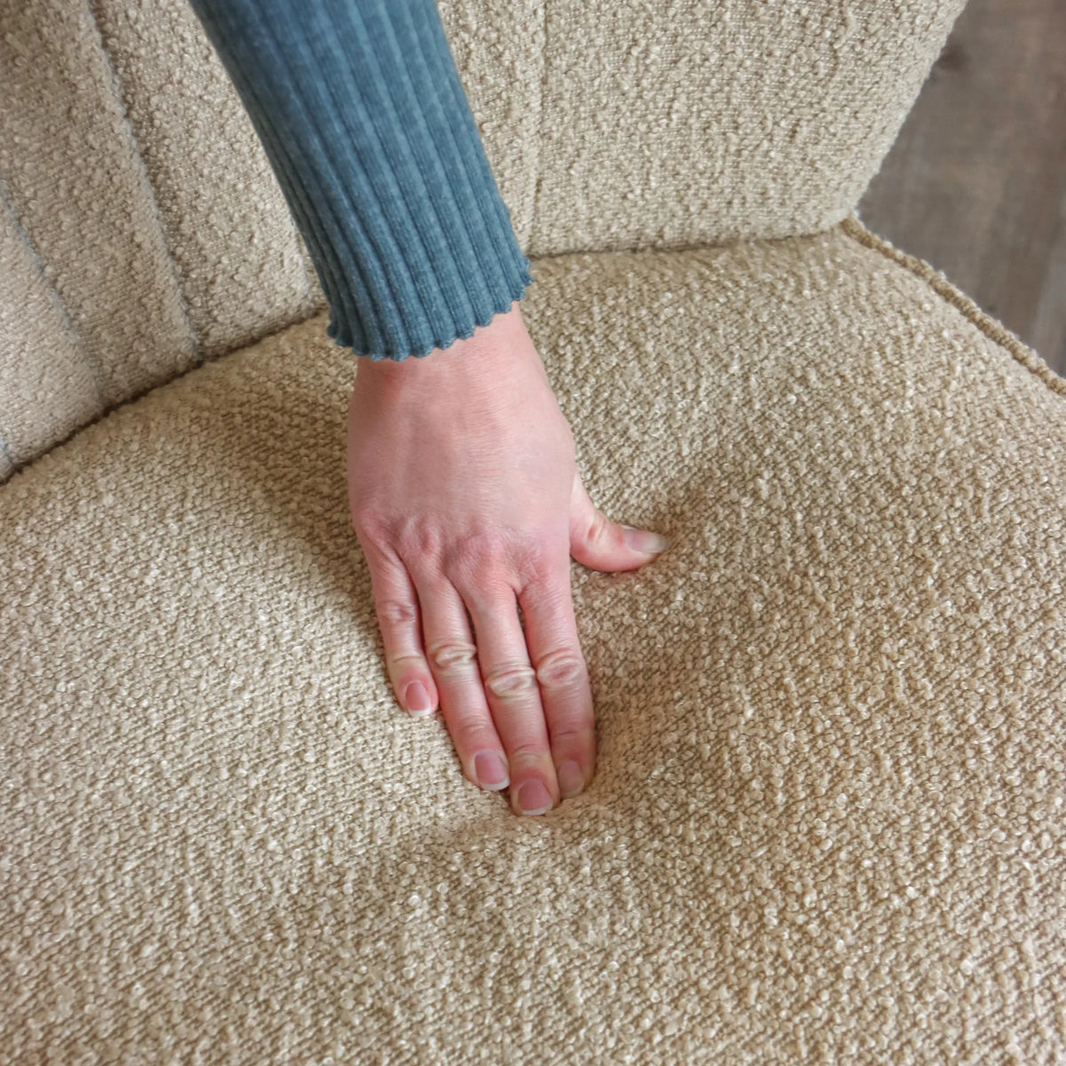 Beige strukturstof fra MANISO loungelænestol med en hånd på sædet fra hjh LIVING