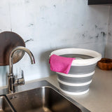 Gråhvid Foldbar beholder CLEAN SILR med en lyserød klud på en arbejdsflade ved siden af en vask fra hjh OFFICE