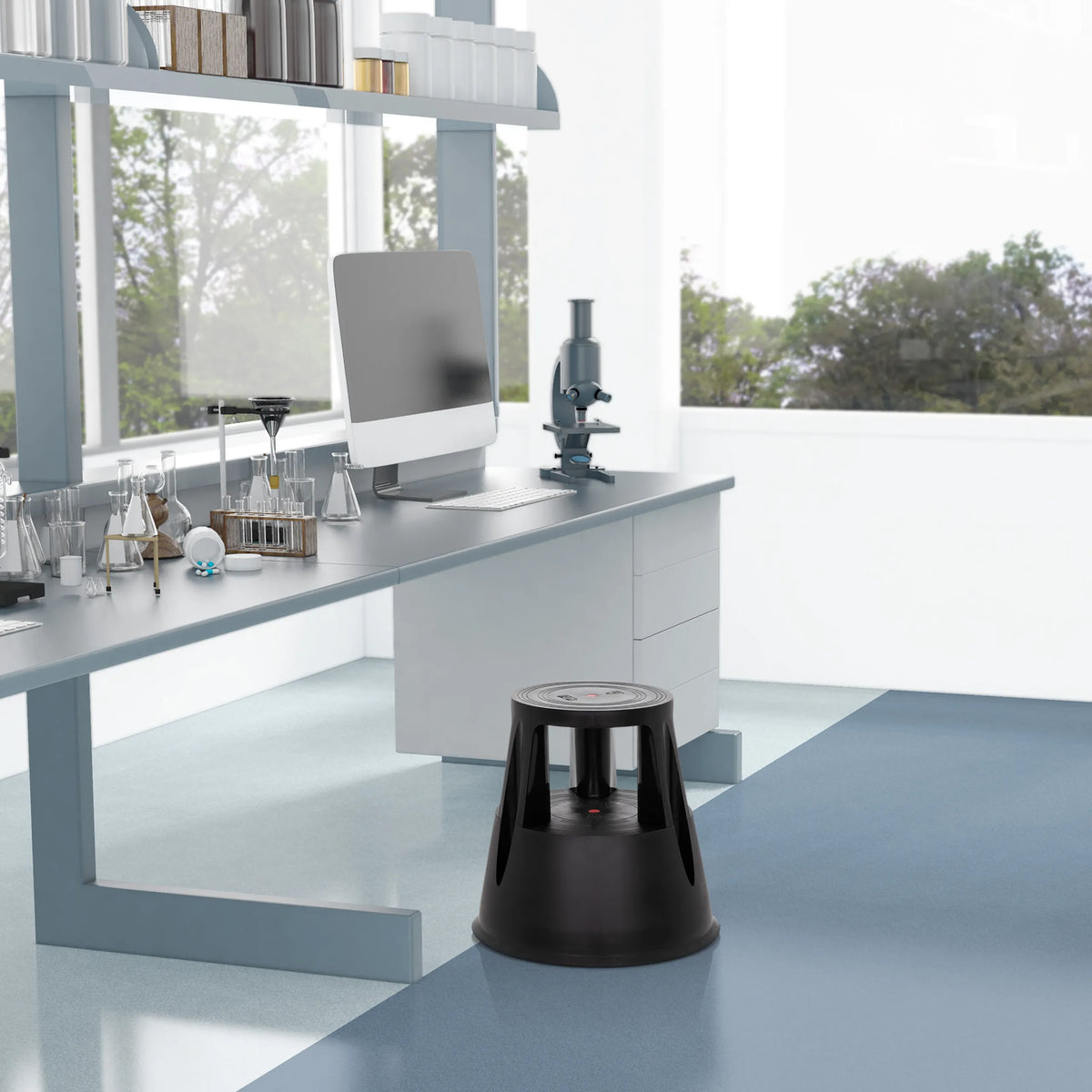Sort trinskammel TIO-M I foran et laboratoriebord i et lyst lokale fra hjh OFFICE