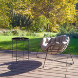 Sort sidebord ALLRUND i metal med hulmønster på en terrasse ved siden af en loungestol fra hjh LIVING